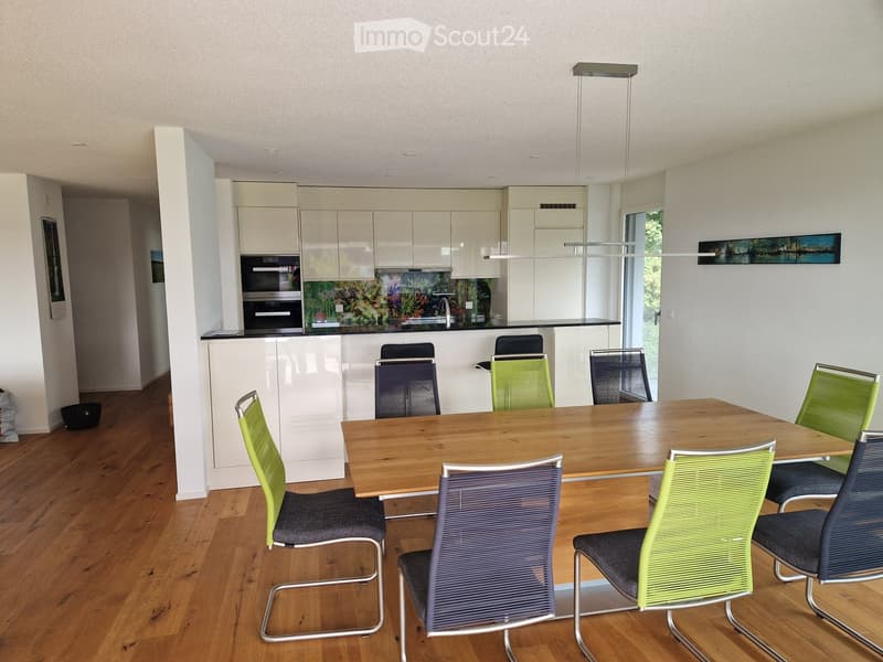 Dining area, wooden table, chairs, kitchen with oven, cabinets, countertops, faucet, island bar, lamps, microwave