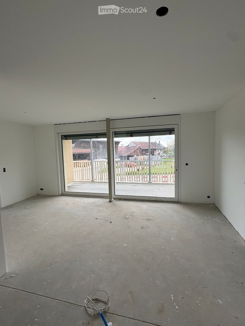 Empty room with concrete floor, white walls, and large sliding glass doors leading to an outdoor area.
