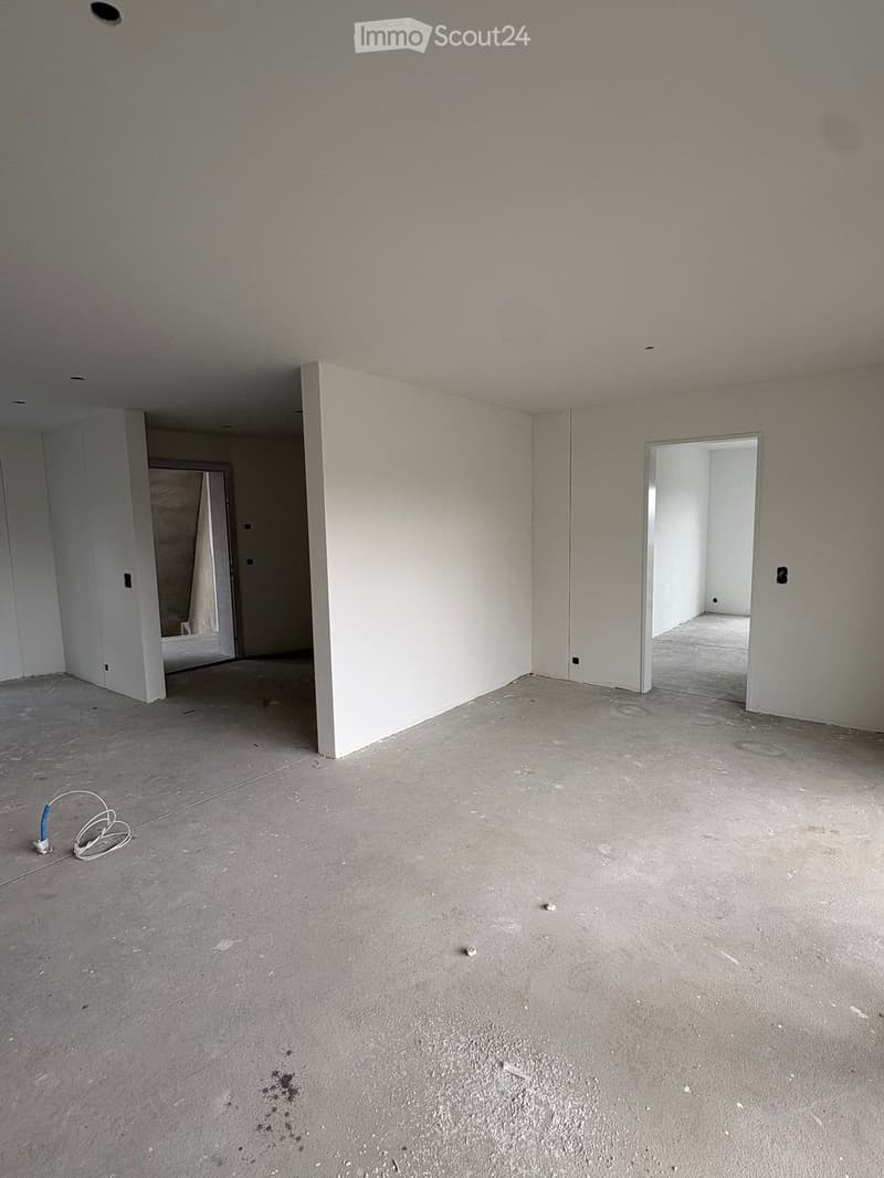 Empty room with bare walls and concrete floor, featuring two open doorways leading to adjacent spaces.