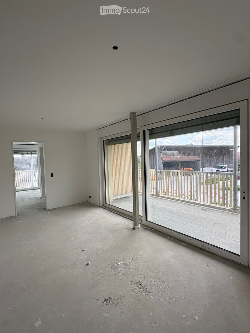 Empty room with concrete floor, white walls, and large sliding glass doors leading to an outdoor area.