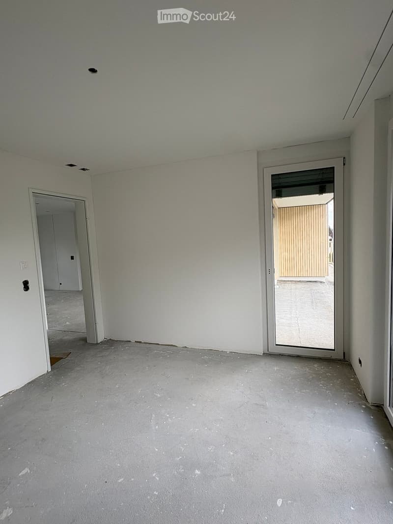 Empty room with concrete floor, white walls, and two doors, one leading to another room and the other to an outdoor area.