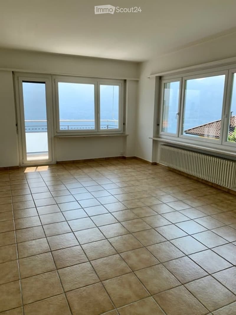 Empty room with tiled floor, large windows, and a balcony view of the sea.