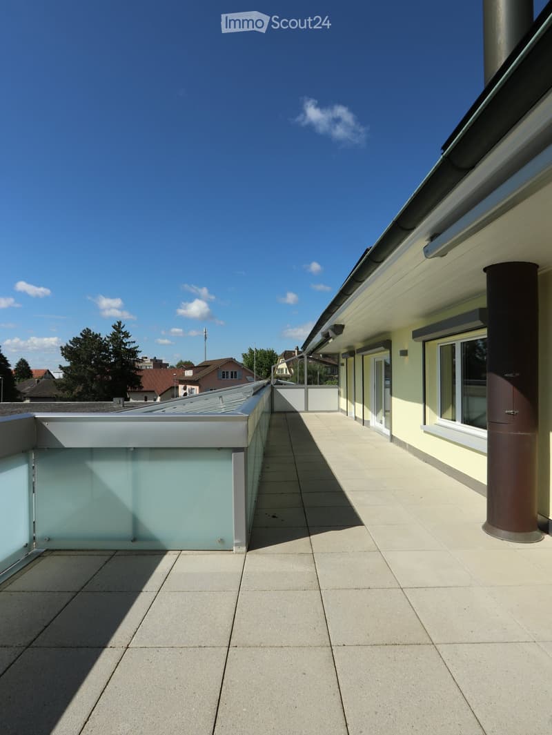 Balcony / Terrace. Roof terrace with tiled flooring, glass railing, and adjacent building with windows and chimney.