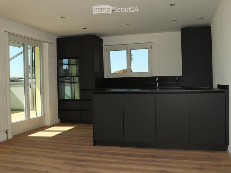 Kitchen. Modern kitchen with dark grey cabinets, a central island, and a sink, featuring large windows and wooden flooring.