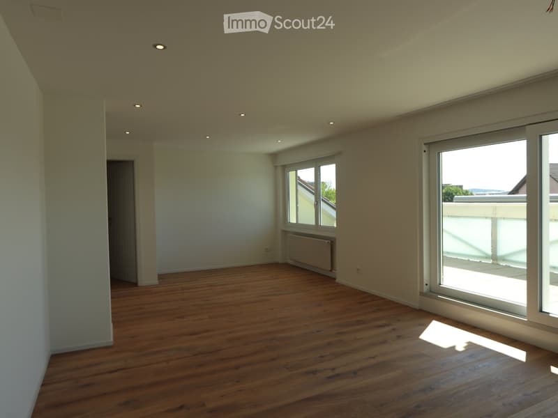 Unfurnished Room. Empty room with wooden flooring, white walls, and large windows offering a view of the balcony and outdoor area.
