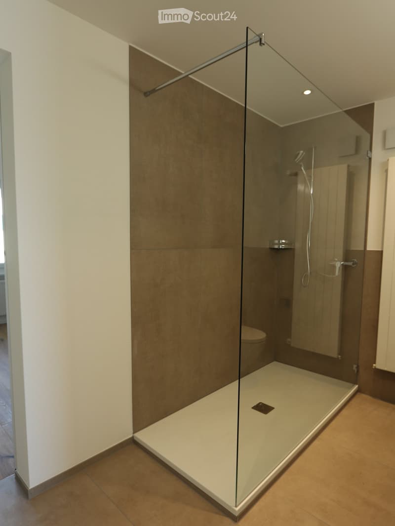 Bathroom. Modern bathroom with a glass-enclosed shower stall and a toilet visible behind the glass. The shower has a sleek, contemporary design with a built-in seat and a modern faucet.