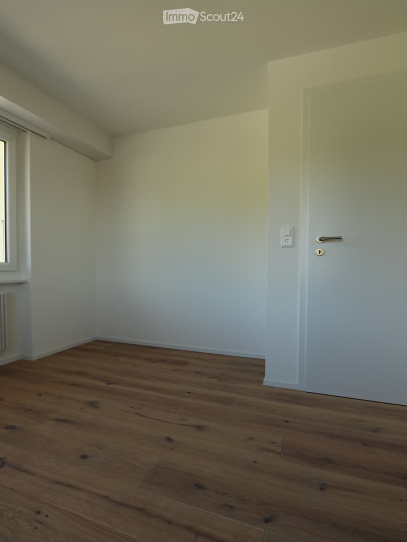 Unfurnished Room. Empty room with wooden flooring, white walls, and a closed door.