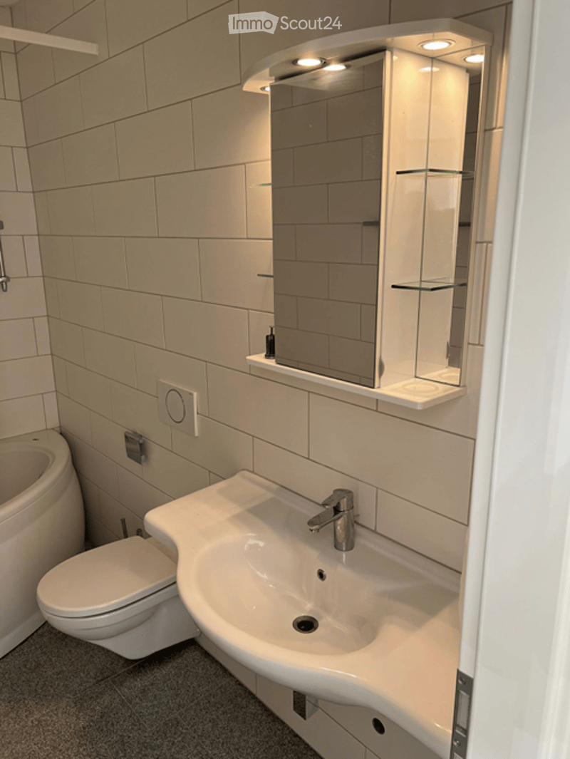 Bathroom. Modern bathroom with white tiles, a sink with a chrome faucet, a mirror cabinet, and a toilet.