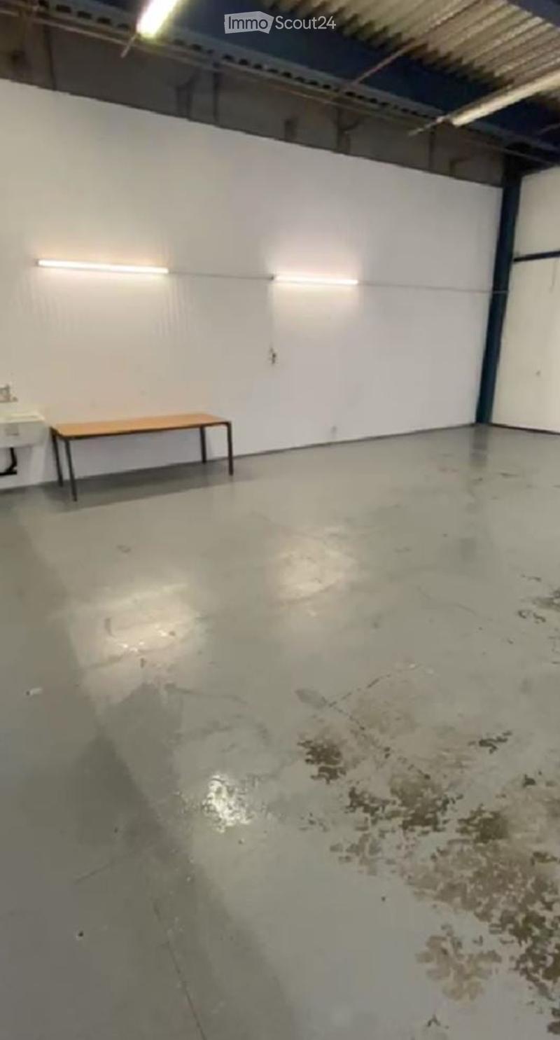 empty room with white walls, concrete floor, ceiling lights, sink with faucet, wooden bench
