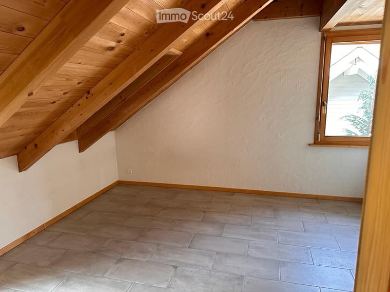 Unfurnished Room. Empty attic room with wooden beams, tiled floor, and a single window letting in natural light.