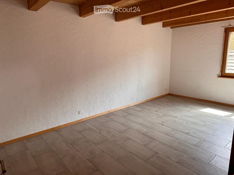 Unfurnished Room. Empty room with light-colored tiled flooring and white walls, featuring exposed wooden beams on the ceiling and a single window on one wall.
