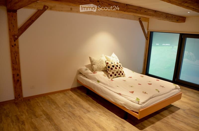 Bedroom. Cozy bedroom with wooden bed frame, floral-patterned bedding, and large window offering a view.