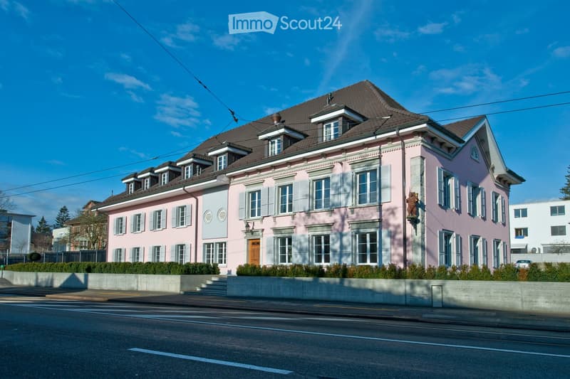 two story building, pink facade, brown roof, several windows, brown door