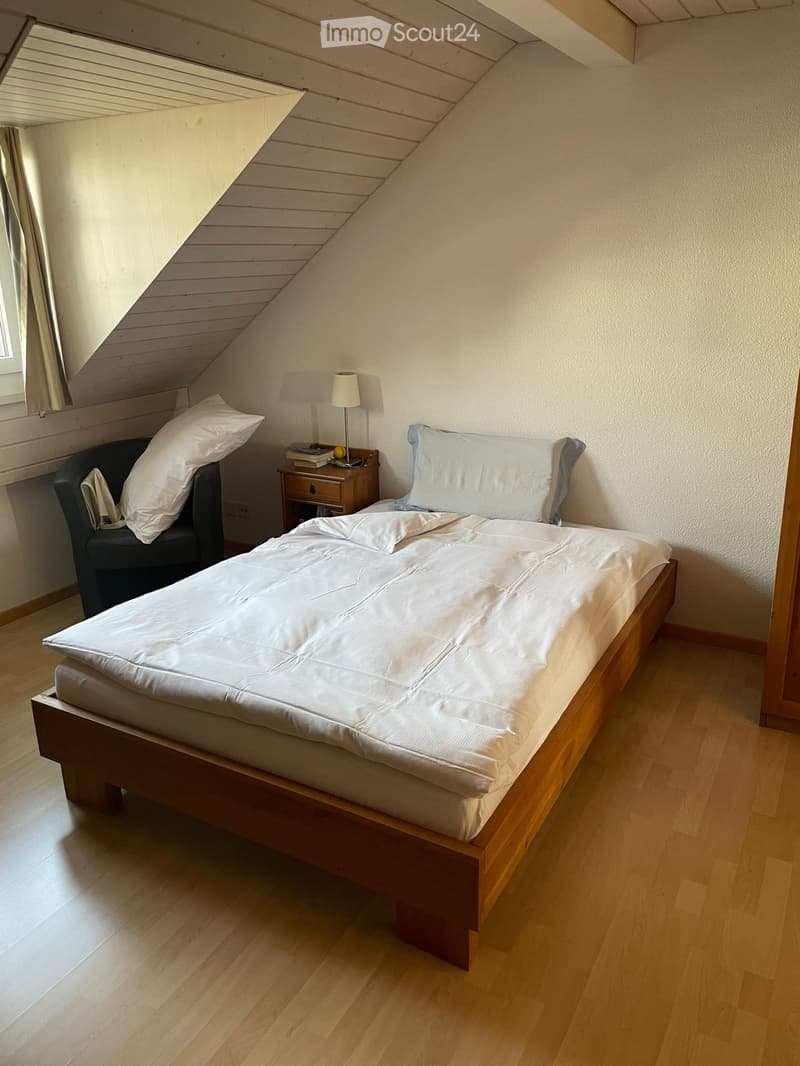 Bedroom with a bed, wooden nightstand, lamp, and chair.