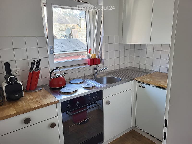 Modern kitchen with white cabinets, wooden countertops, stainless steel sink, electric stove, and various appliances.