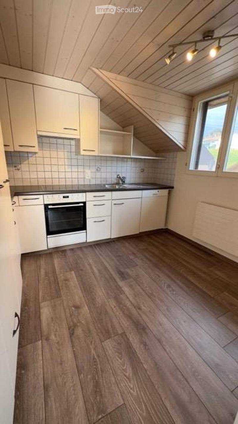 Bright kitchen with white cabinets, wooden flooring, and a view through a window. Includes a sink, faucet, oven, and drawers.