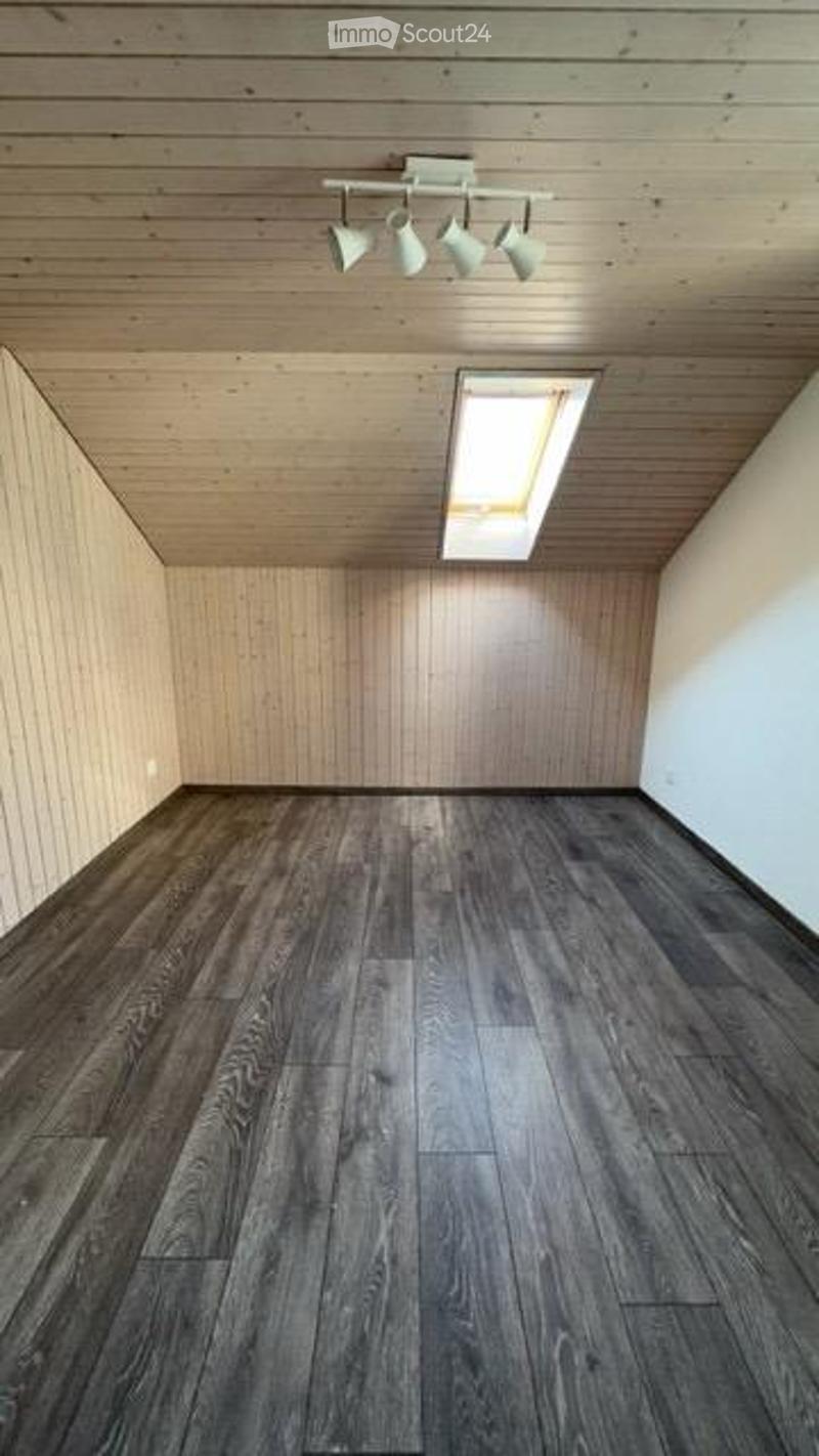 Completely empty room with wooden walls, dark wooden floor, and a skylight window. No furniture or equipment.
