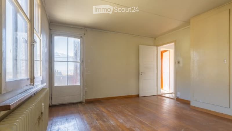 Empty room with wooden flooring, white walls, and large windows. No furniture or equipment present.