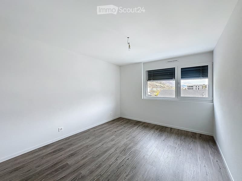 Empty room with light grey walls, wooden flooring, and a window with blinds. No furniture or equipment present.