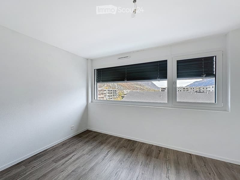 Empty room, white walls, wooden floor, two large windows, power outlet, light fixture