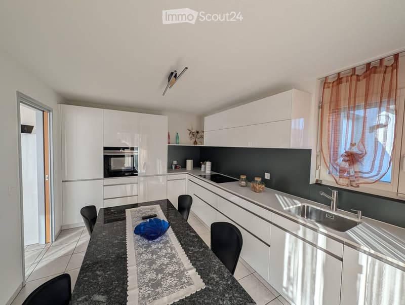 modern kitchen with white cabinetry, granite countertop, black appliances, and a dining table