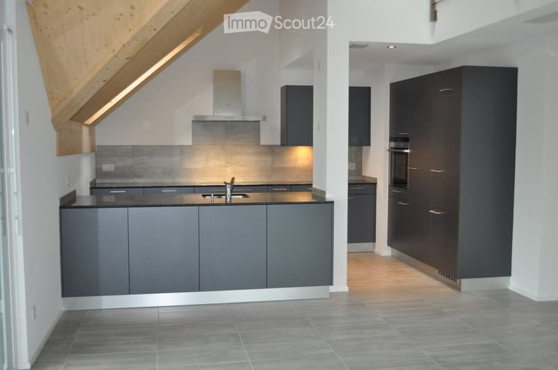 Modern kitchen with grey cabinets, stainless steel appliances, and a sleek design. Features include a central island with a sink and faucet, built-in oven, and range hood.