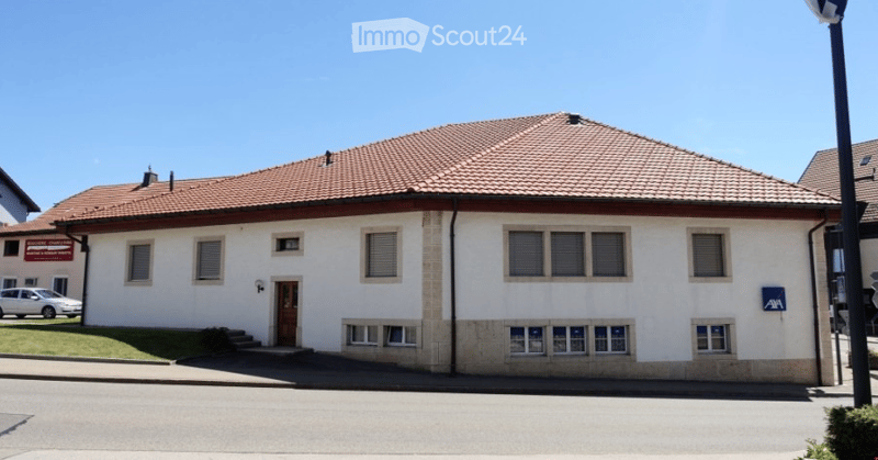 white house with a brown tiled roof, multiple windows, front door, parked car
