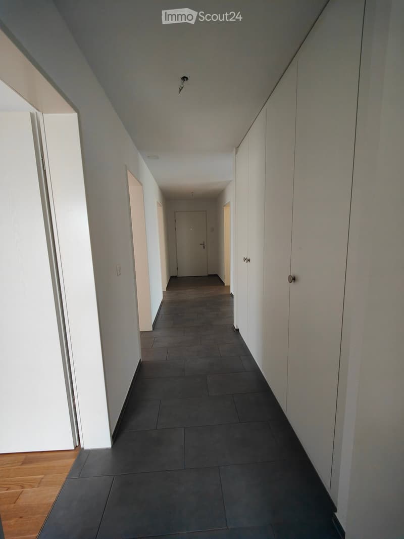 Modern hallway with dark tiled floor, white walls, and several doors leading to other rooms.