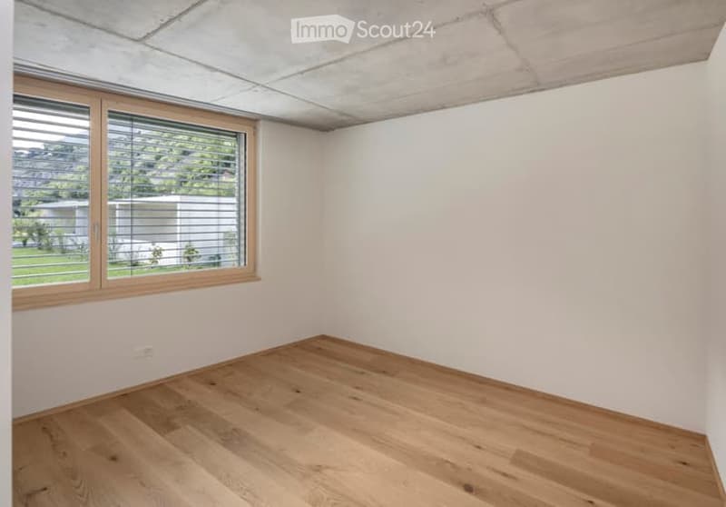 Empty room with wooden flooring, white walls, and a large window with blinds. No furniture or equipment present.