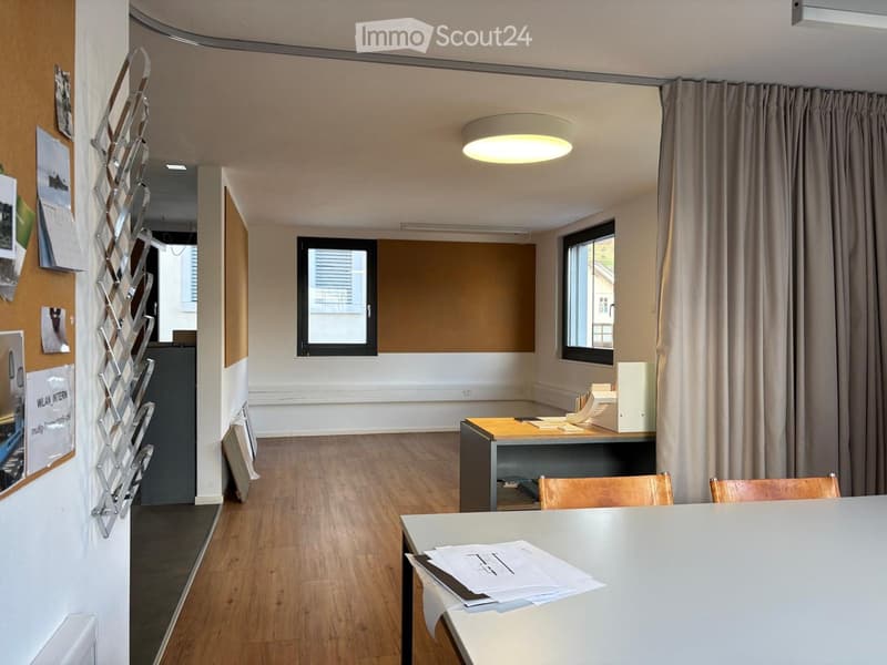 Wooden floor, white walls, large open space, tables, chairs, two windows, ceiling lights