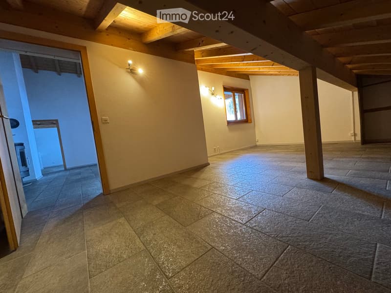 Empty room with exposed wooden beams, tiled floor, and a single window letting in natural light. The space is clean and unfurnished, with no visible furniture or equipment.