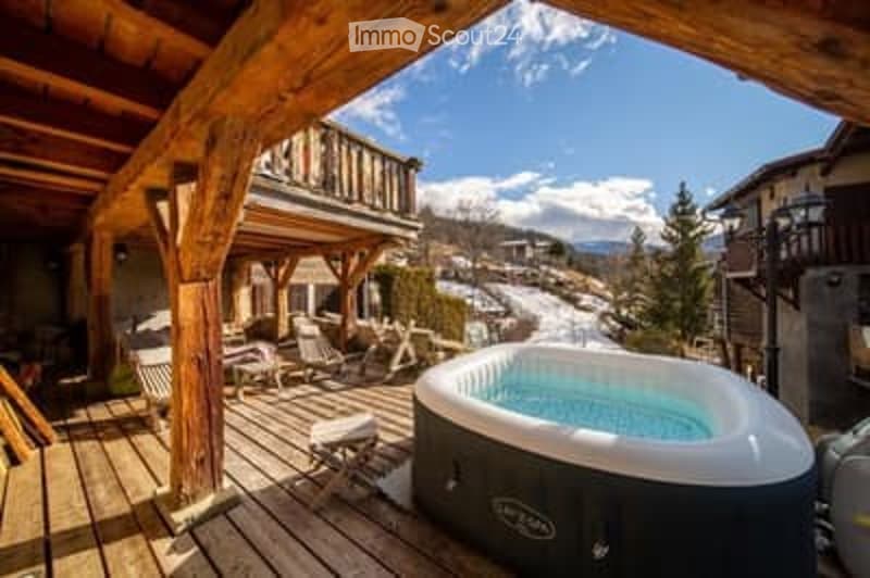 Wooden deck area with a hot tub, lounge chairs, and a scenic mountain view.