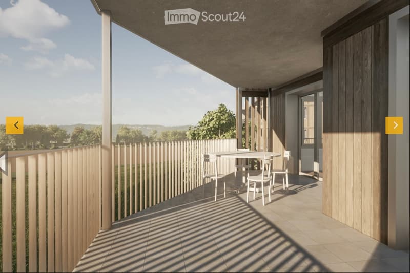 Balcony with a wooden railing, tiled floor, and a small table with chairs, overlooking a green landscape.