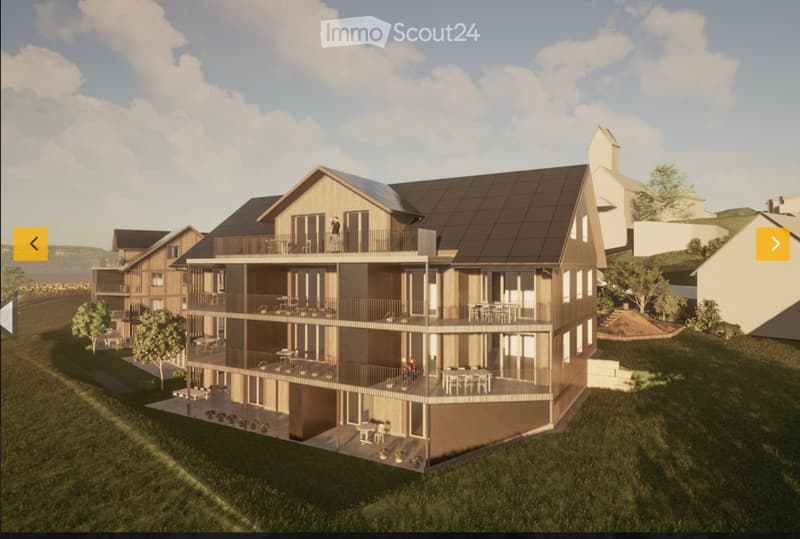 3D rendering of a modern multi-story residential building with wooden balconies, large windows, and a sloped roof. The building features multiple levels with outdoor seating areas and is surrounded by greenery and a grassy lawn.