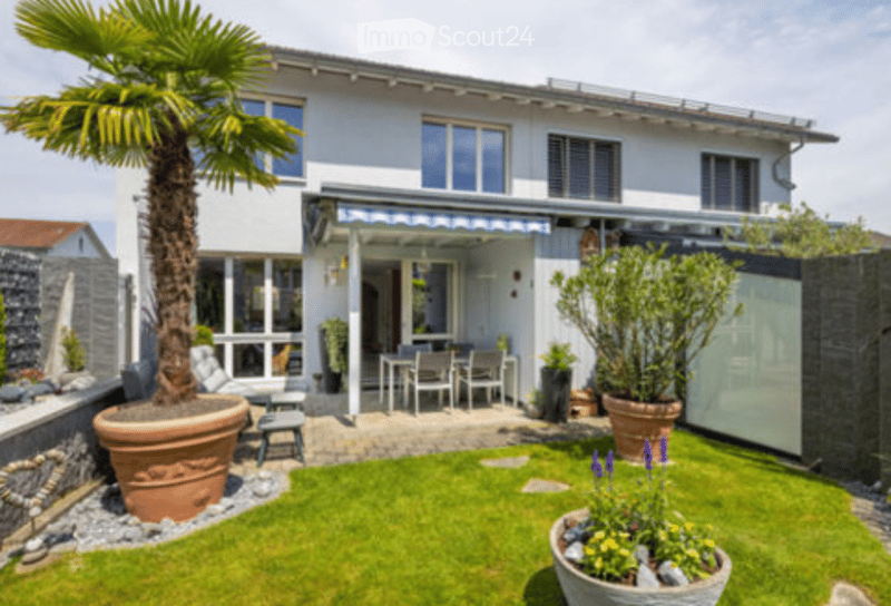 Garden / Outdoor Area. Well-maintained garden area with a palm tree, patio furniture, and colorful flowers.