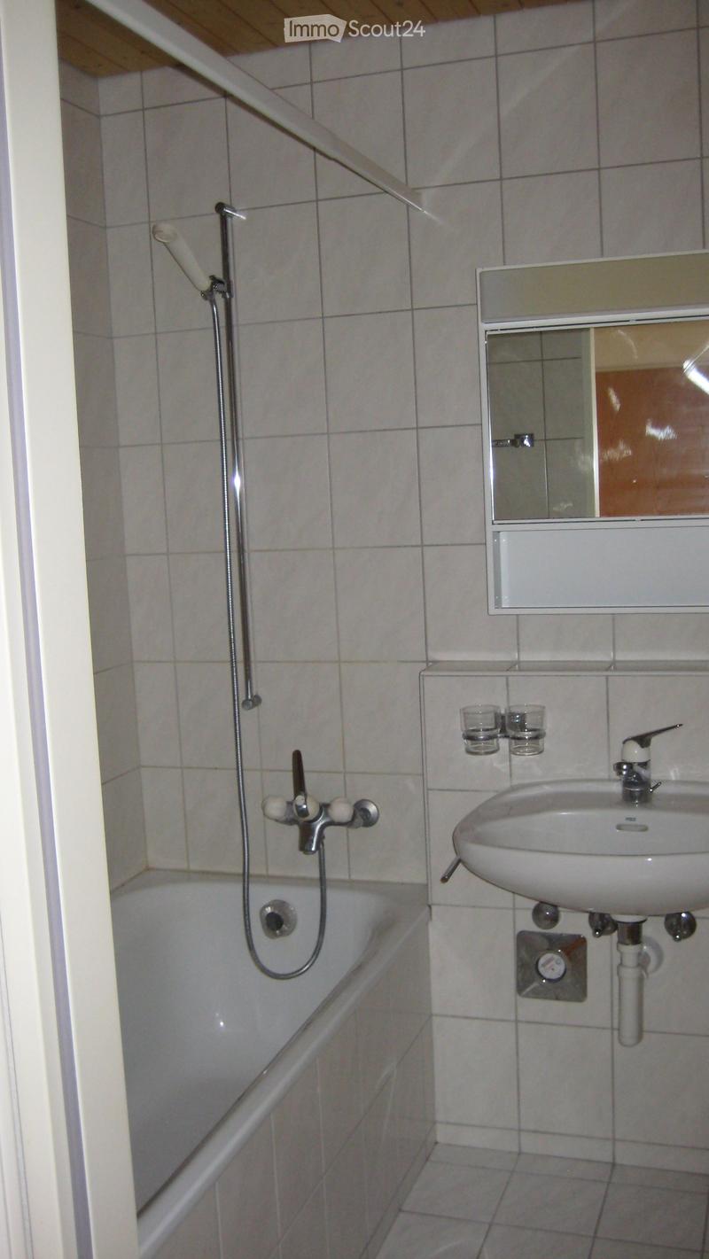 Bathroom with a bathtub, sink, mirror, and two cups on a shelf.