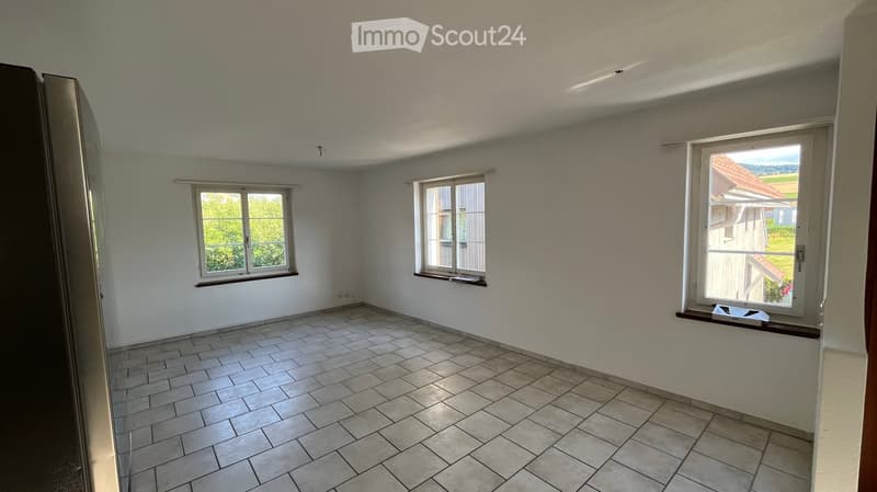 Empty room with tiled floor, three windows, and white walls. No furniture or equipment present.
