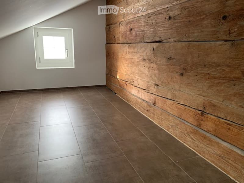 Empty room with wooden plank wall, tiled floor, and a small window with white frame.