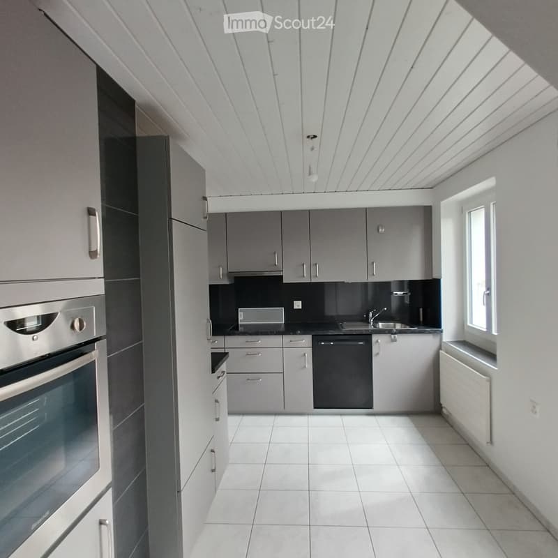 Modern kitchen with grey cabinets, white tiled floor, stainless steel oven, sink, and dishwasher.