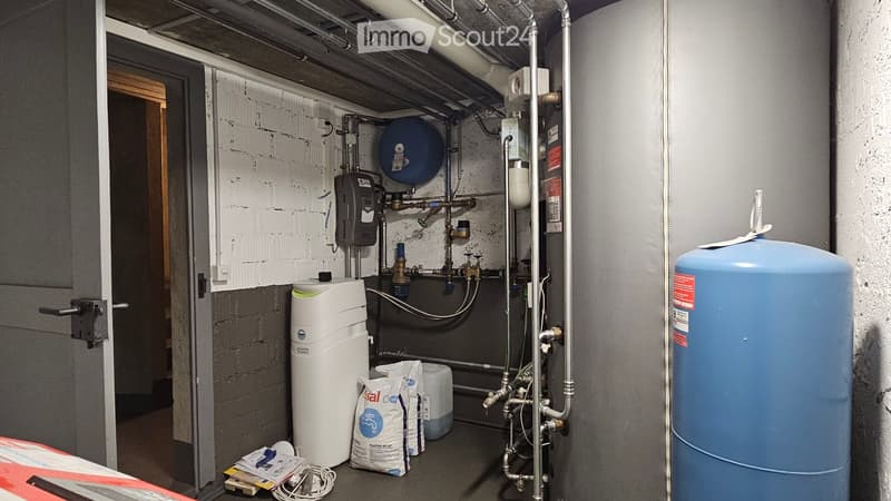 Utility room with water heater, pressure vessel, pipes, valves, bags, and cables.