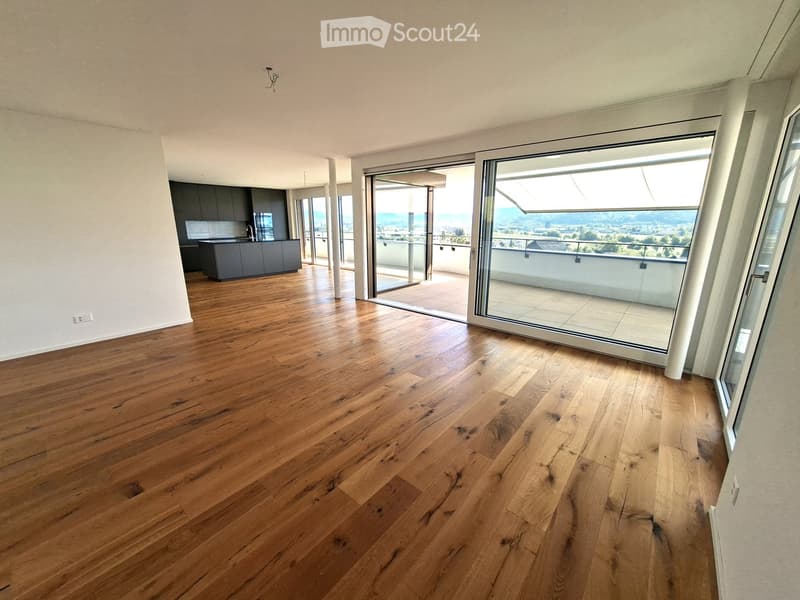 Empty room with wooden flooring, large sliding glass doors leading to a balcony with scenic views.
