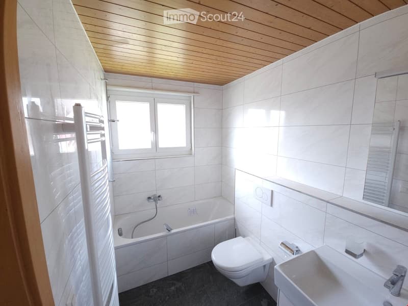 Bathroom with a white bathtub, toilet, sink, wooden ceiling, white tiled walls
