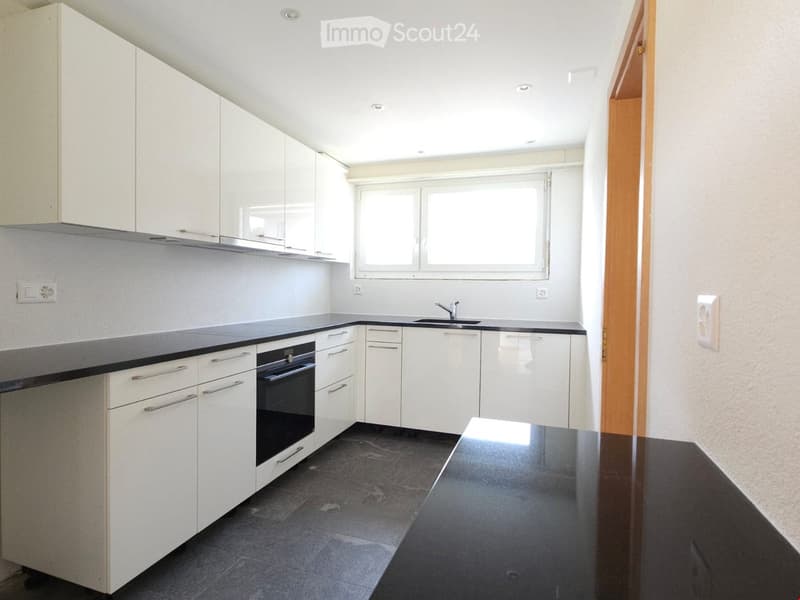 White cupboards, black countertop, open oven, window, sink, and faucet