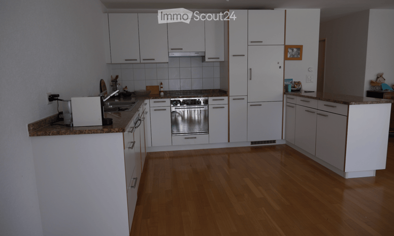 Modern kitchen with white cabinets, granite countertops, wooden flooring, and stainless steel appliances including a sink, oven, and microwave.