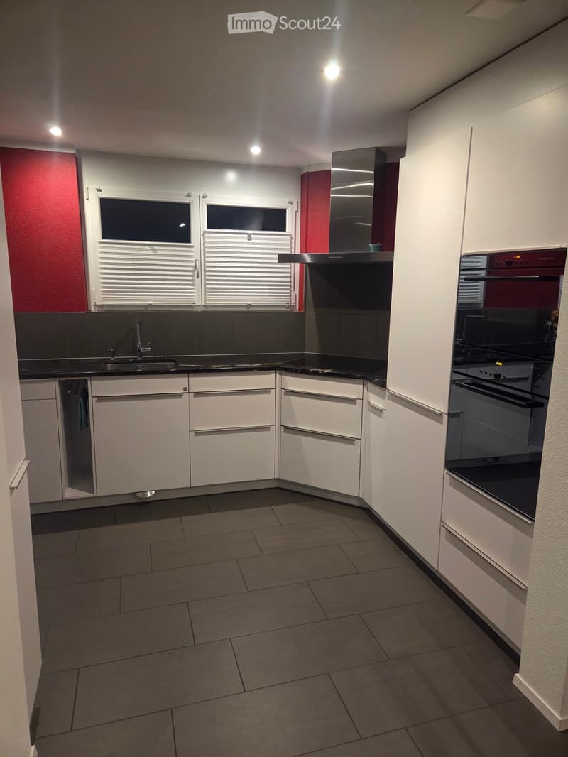 Modern kitchen with white cabinets, black countertops, and stainless steel appliances. Features a sink with a faucet, an oven, and built-in cabinets.