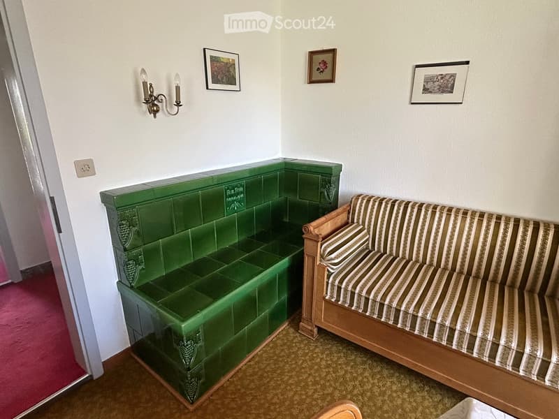 Living room with a green tiled bench and a striped sofa, decorated with framed pictures and a wall-mounted candle holder.