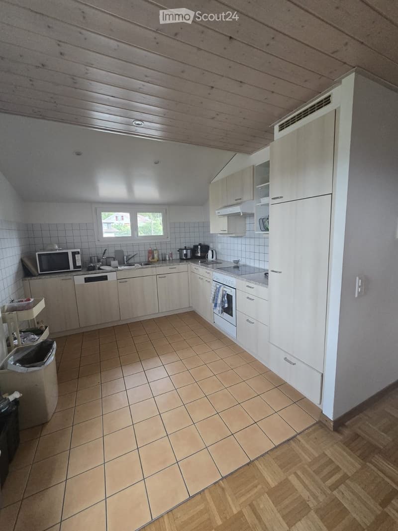 Modern kitchen with white cabinets, tiled floor, and wooden accents. Features a microwave, dishwasher, oven, and various appliances.