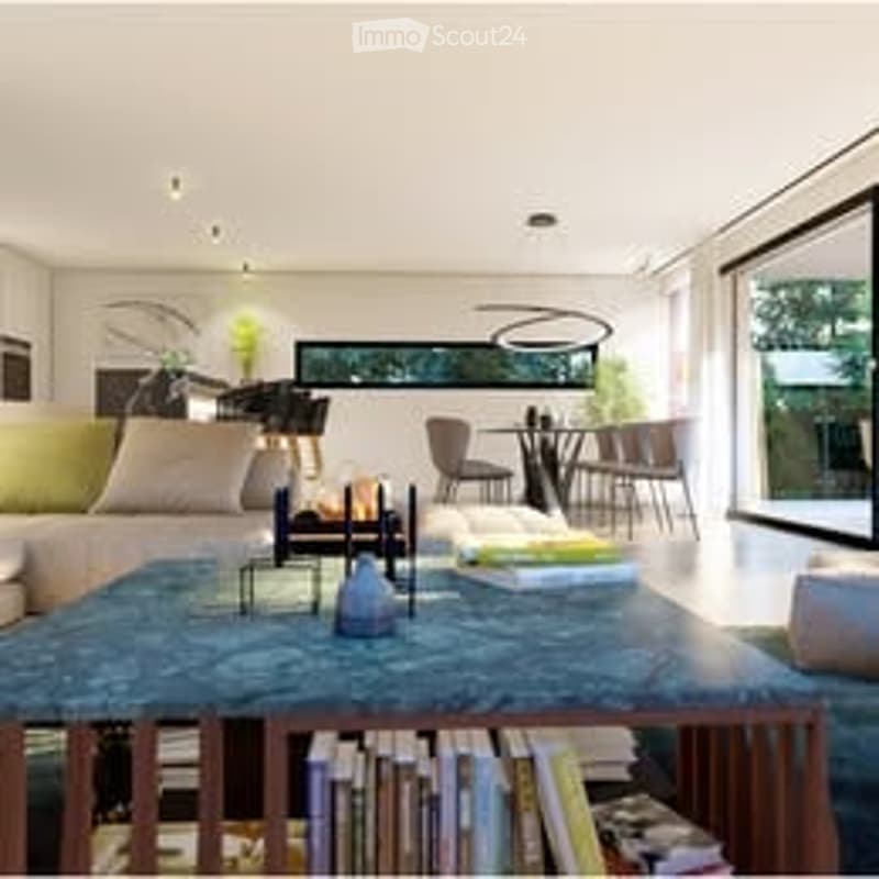 Modern living room with large windows offering a view, a grey sofa, a coffee table with books, a dining area with chairs and a table, and a bookshelf filled with books.