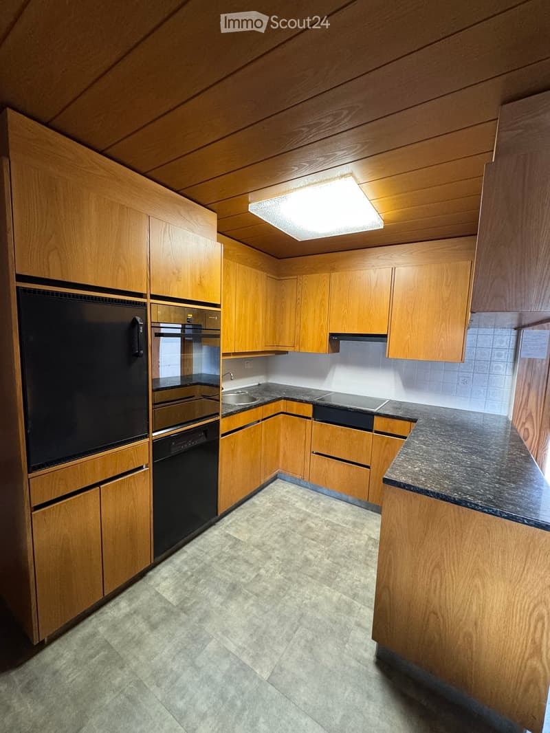 Modern kitchen with wooden cabinets, granite countertops, and stainless steel appliances including a refrigerator, oven, and stove.