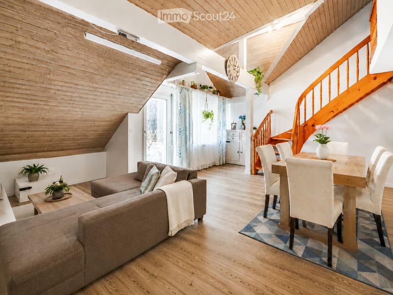 Bright living and dining area with wooden floors, a curved staircase, and modern furnishings including a sofa, coffee table, dining table, and chairs.